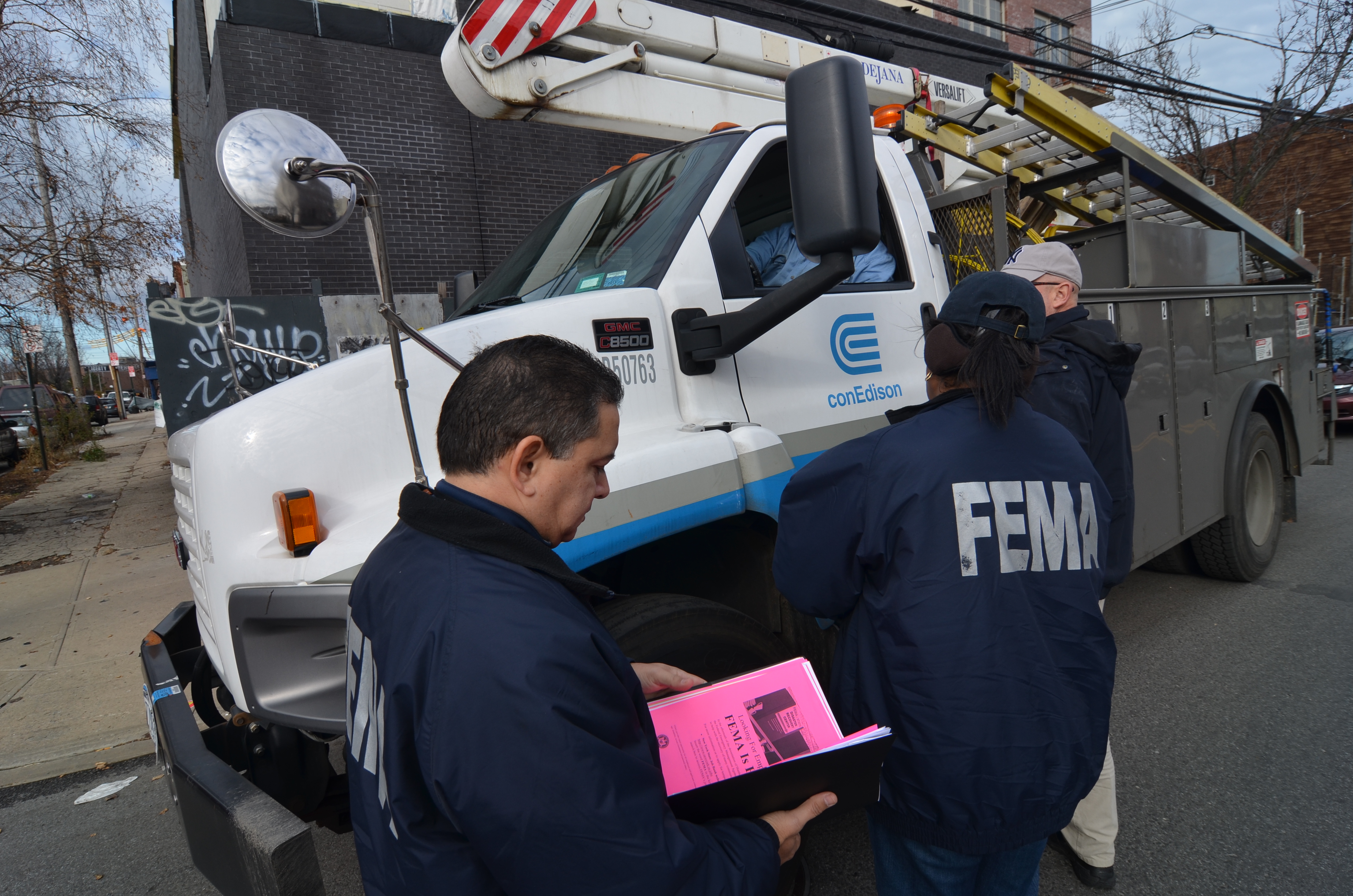 New York City, N.Y., Dec. 11, 2012 -- FEMA Community Relations employees discuss the restoration of electric service in the Red Hook area of Brooklyn with employees of NYC's Con Edison electric company. The speedy repair of old electrical infrastructure in the New York City area has frustrated residents and business people in the aftermath of Hurricane Sandy. Walt Jennings/FEMA